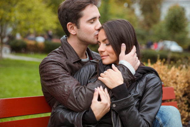 Portrait of a beautiful young couple hugging outdoors on the bench