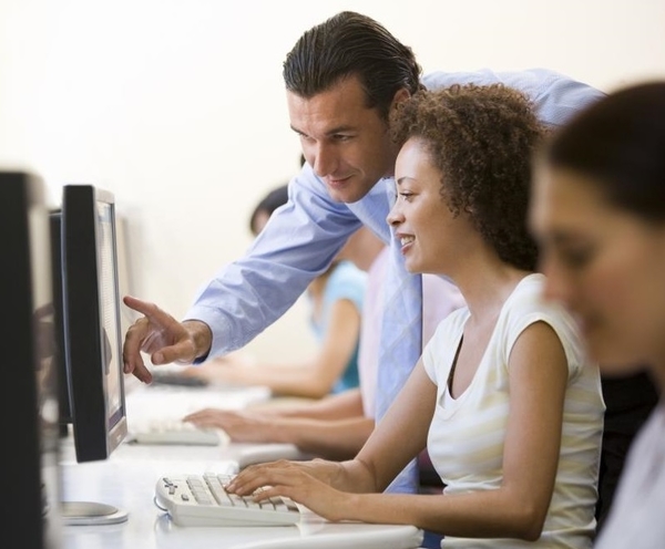 Man assisting woman in computer room