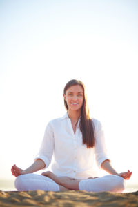 Meditating woman sitting in pose of lotus against clear sky outdoors