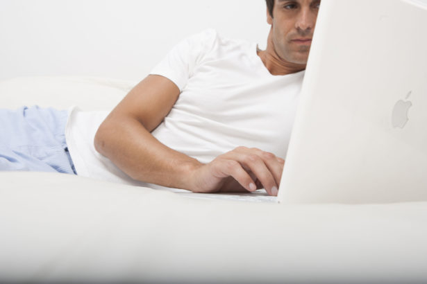 Man using laptop in bed