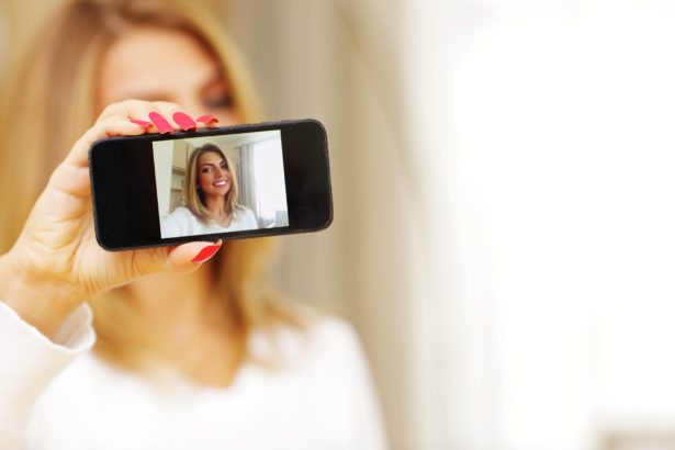 Young woman making self-photo on smartphone
