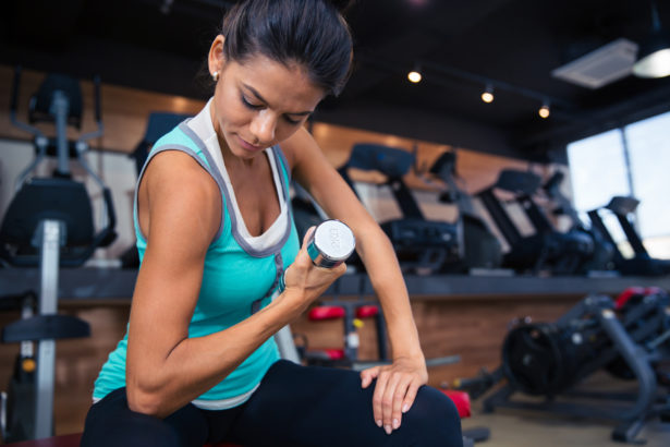 Girl workout with dumbbell on the bench