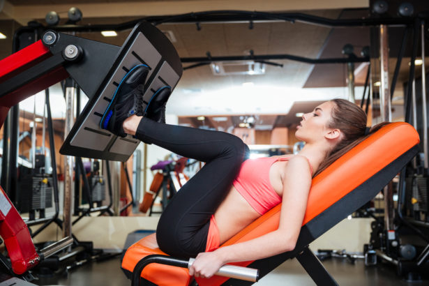 Strong sportswoman doing fitness exercises for legs muscles in gym