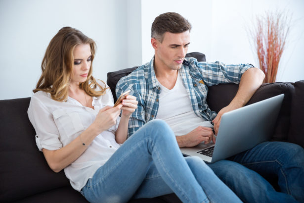 Beautiful couple using laptop and smartphone separately