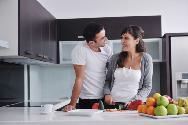 happy young couple have fun in  modern kitchen indoor  while preparing fresh fruits and vegetables food salad