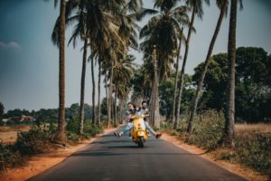 Couple riding bike by coconut trees